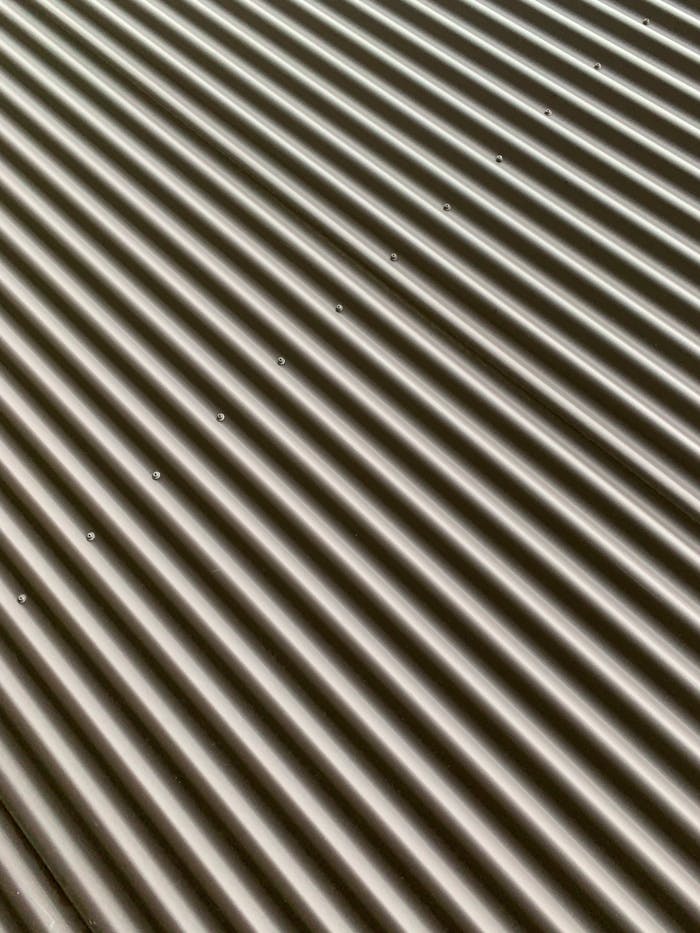 about-us Detailed view of a corrugated metal sheet showcasing texture and pattern.